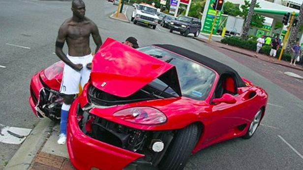 Mario Balotelli steht neben seinem beschädigten roten Ferrari.