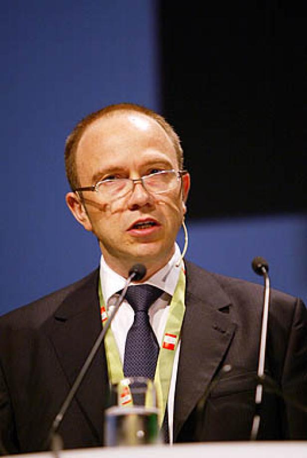 Ein Mann mit Brille und Anzug spricht auf einer Konferenz.