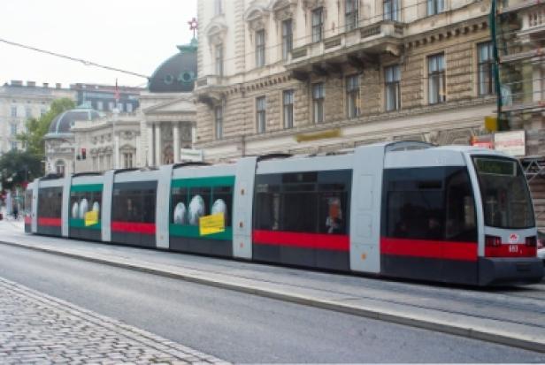 Eine moderne Straßenbahn fährt durch eine Stadt mit klassischer Architektur.