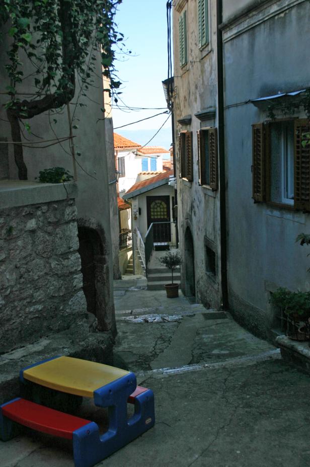 Eine Gasse mit Treppen und alten Häusern führt bergauf.