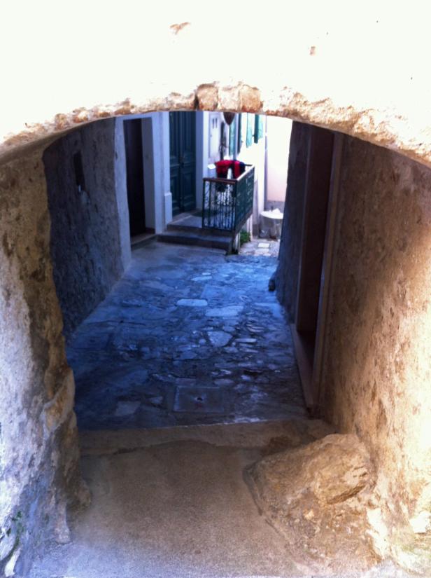 Ein Blick durch einen steinernen Torbogen auf eine Gasse.