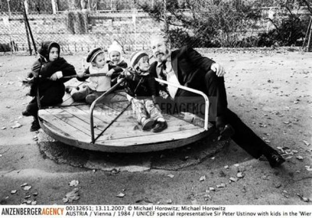 Sir Peter Ustinov mit Kindern auf einem Karussell in Wien, 1984.