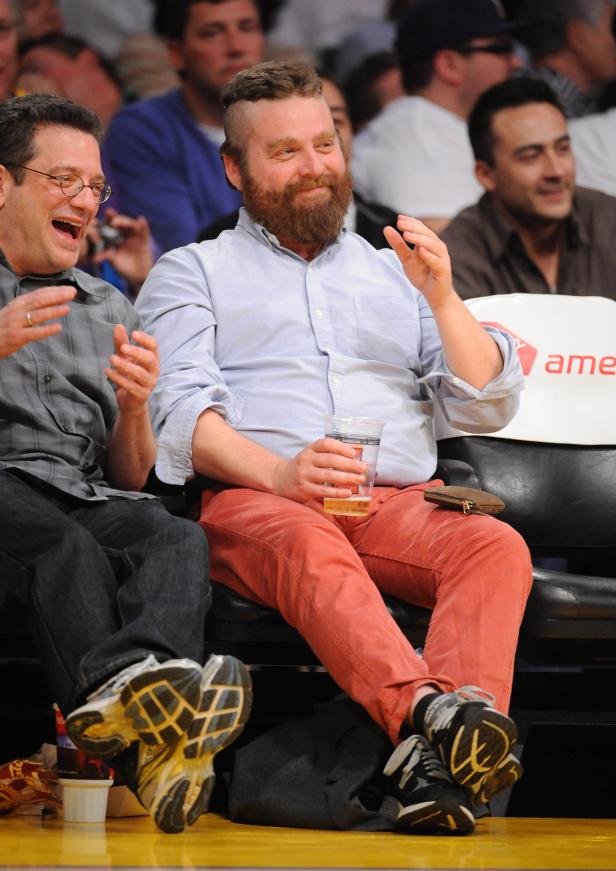 Zach Galifianakis sitzt mit einem Bier in der Hand bei einem Basketballspiel.