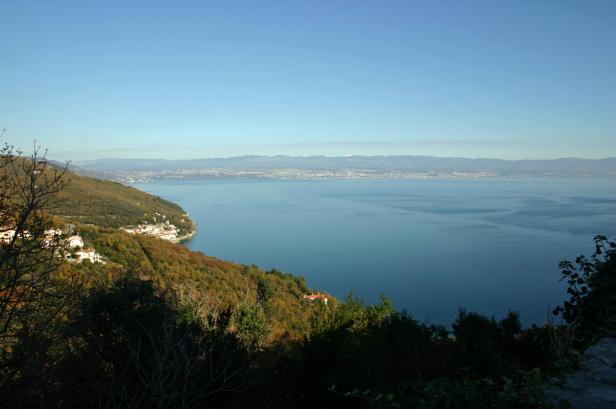 Blick auf eine Küstenlinie mit Häusern und das blaue Meer im Hintergrund.