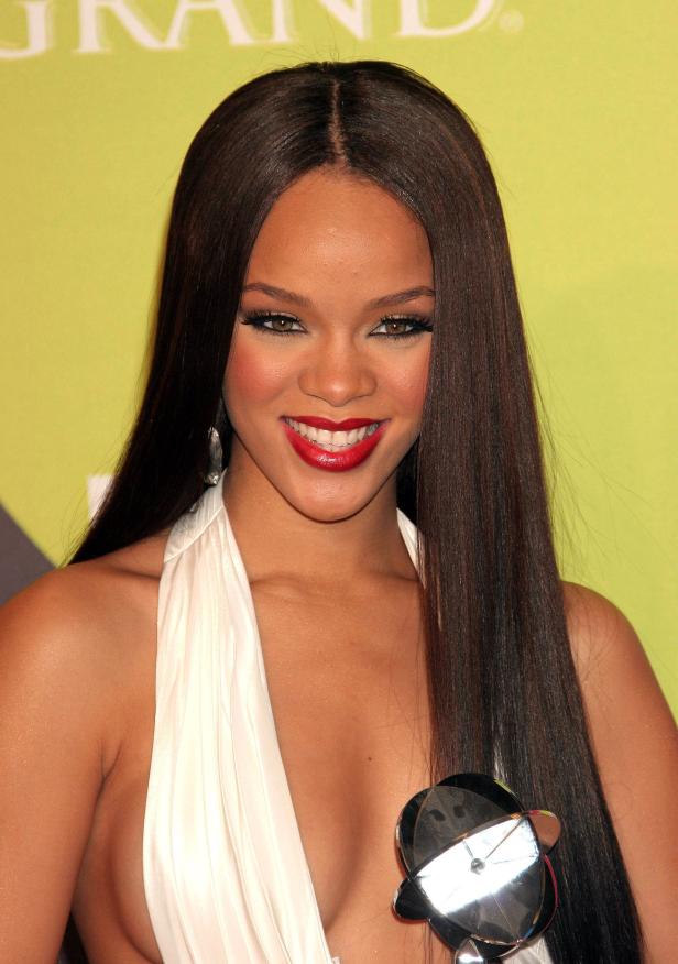 Rihanna lächelt mit einem Preis in einem weißen Kleid.