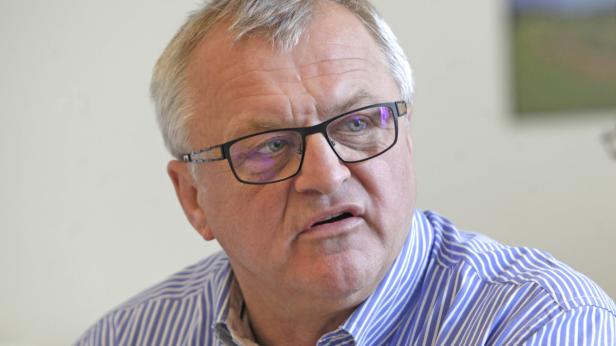 Ein Mann mit Brille und blau gestreiftem Hemd schaut aufmerksam zur Seite.