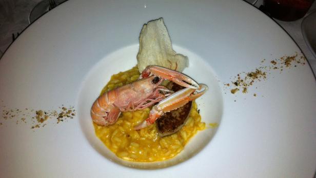 Ein Teller mit Risotto, einer Garnele und einer Scheibe Foie Gras.