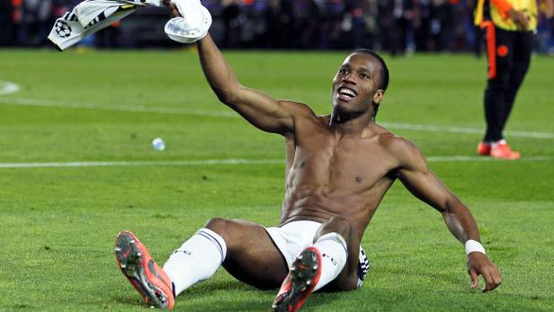 Didier Drogba feiert barfuß und mit einem Trikot in der Hand auf dem Rasen.