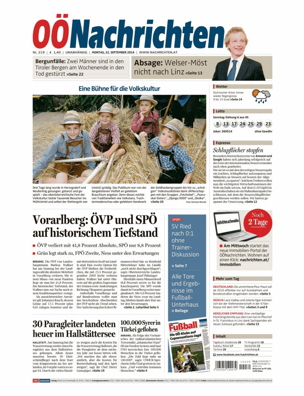 Kinder in Tracht sitzen auf einer Bühne mit Strohballen bei einer Veranstaltung der Volkskultur.