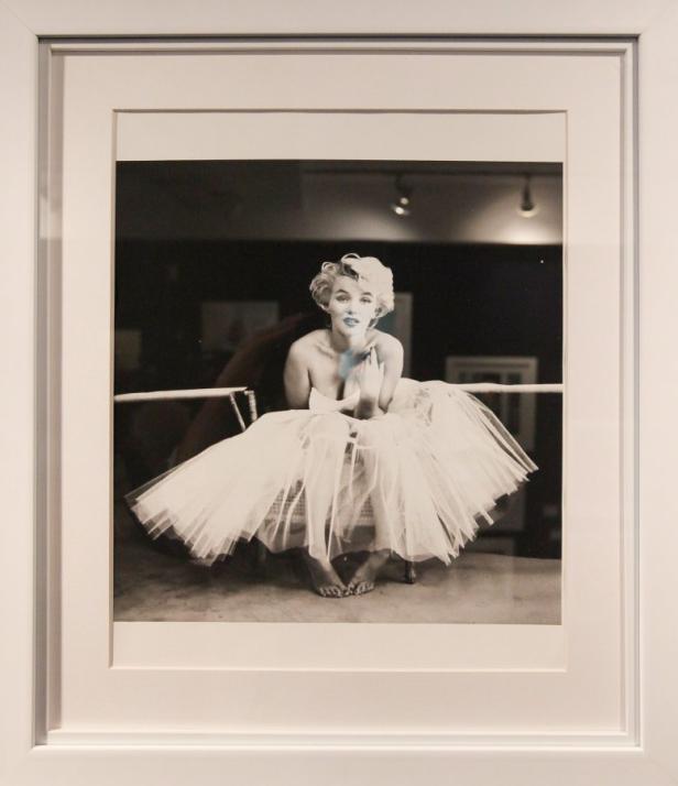 Marilyn Monroe in einem weißen Tutu, sitzend und lächelnd.