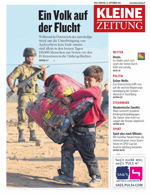 Ein Junge trägt eine schwere Last, während ein Soldat im Hintergrund steht.