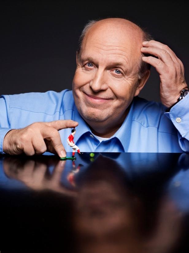 Ein Mann lächelt und spielt mit einer Tischfußballfigur.