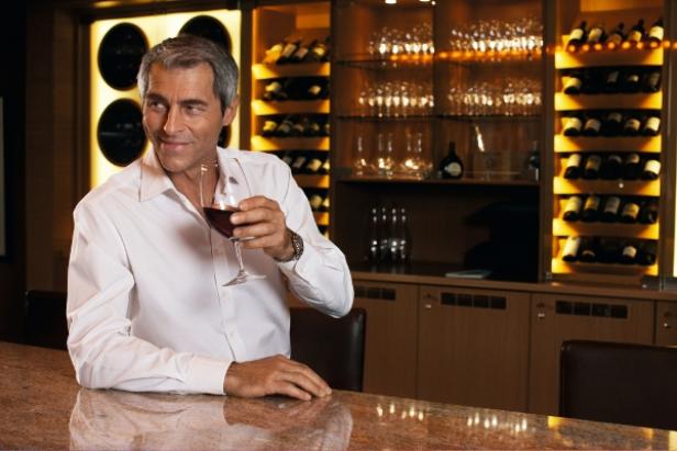 Ein Mann in einem Weinlokal hält ein Glas Rotwein in der Hand.