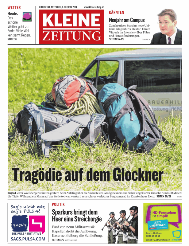 Bergsteigerrucksäcke und Seile liegen im Gras vor einem Fahrzeug der Bergrettung.