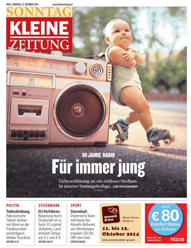 Ein Baby auf Rollschuhen steht neben einem alten Radio auf einer Titelseite der Kleinen Zeitung.