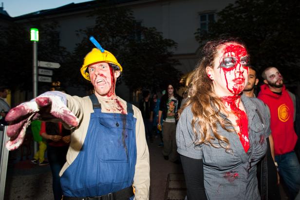 Zwei als Zombies verkleidete Personen mit blutverschmierten Gesichtern stehen auf der Straße.