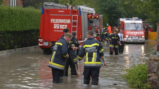Freiwillige Feuerwehr Mödling Feuerwehrleute stehen im Hochwasser und inspizieren die Lage.