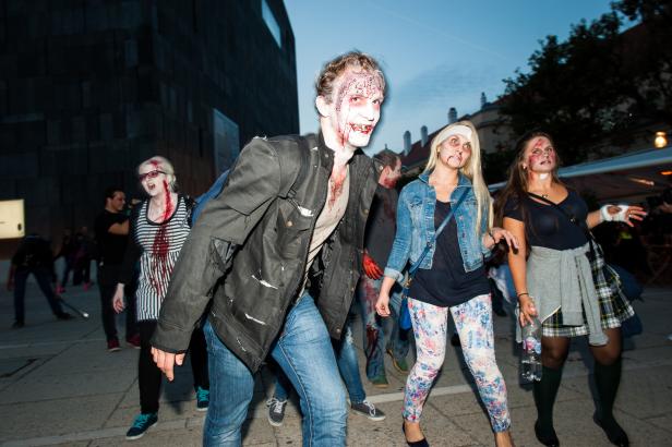 Eine Gruppe als Zombies verkleideter Menschen nimmt an einer Parade teil.