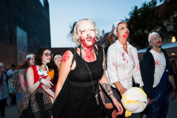 Eine Gruppe als Zombies verkleideter Menschen nimmt an einer Parade teil.