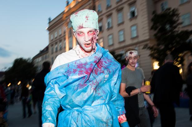 Ein als blutiger Zombie-Arzt verkleideter Mann steht im Freien.
