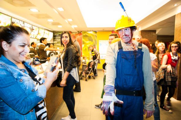 Ein als Zombie verkleideter Bauarbeiter steht in einem Fast-Food-Restaurant.