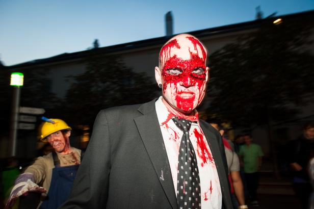 Ein Mann mit blutverschmiertem Gesicht und Anzug blickt in die Kamera.