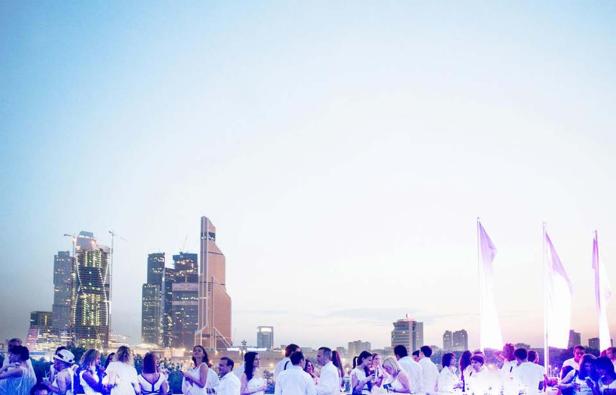 Eine Gruppe von Menschen in weißer Kleidung vor der Skyline einer Stadt.