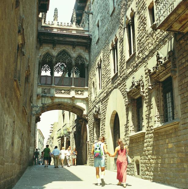 Ein Paar geht Händchen haltend durch eine Gasse in Barcelona.