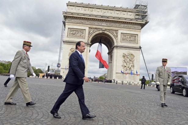 François Hollande geht mit zwei Militärangehörigen am Arc de Triomphe entlang.