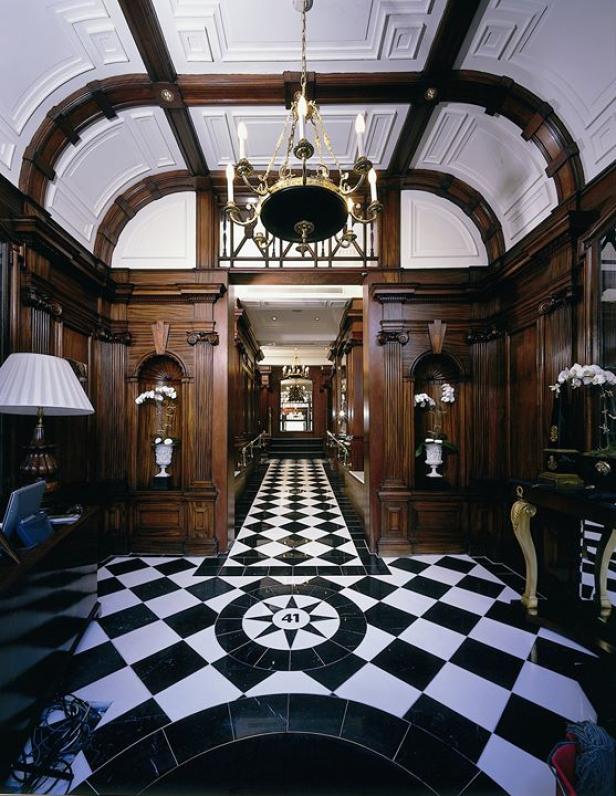 Ein luxuriöser Flur mit Schachbrettmusterboden und dunkler Holzvertäfelung.