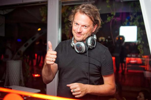 Ein DJ mit Kopfhörern um den Hals gibt einen Daumen nach oben.