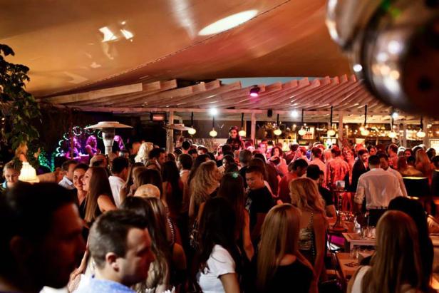 Viele Menschen feiern in einer Bar oder einem Club unter einem Zeltdach.