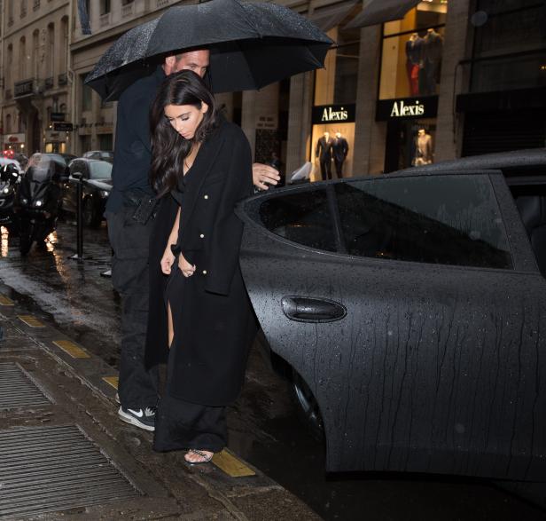 Kim Kardashian steigt im Regen aus einem Auto.