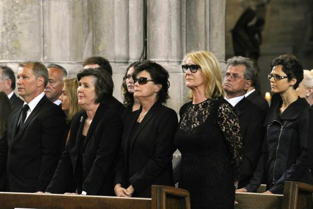Eine Gruppe von Menschen in dunkler Kleidung steht in einer Kirche.