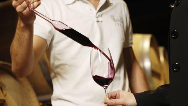 Rotwein wird mit einer Pipette in ein Glas gefüllt.