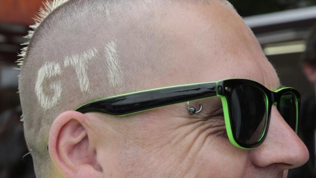Ein Mann mit einer „GTI“-Rasur und einer schwarz-grünen Sonnenbrille.