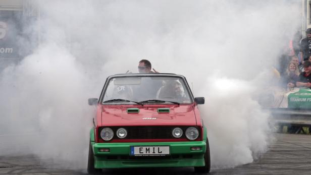 Ein roter und grüner VW Golf Cabriolet erzeugt eine Rauchwolke.