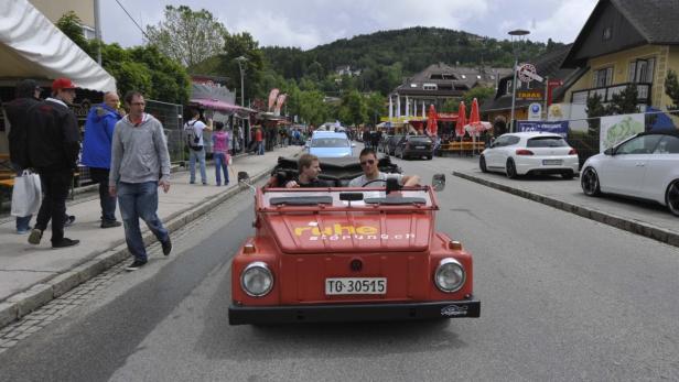 GTI,treffen,worthersee,2014 Zwei Männer fahren in einem roten VW Kübelwagen durch eine Stadt.
