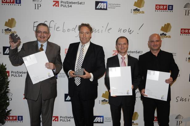 Vier Männer in Anzügen posieren mit Auszeichnungen bei den Effie Awards Austria 2014.