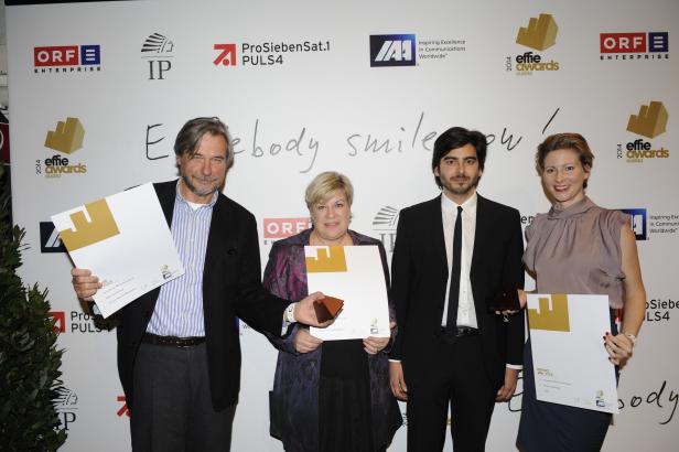 Vier Personen posieren mit Effie Awards vor einer Wand mit Logos.