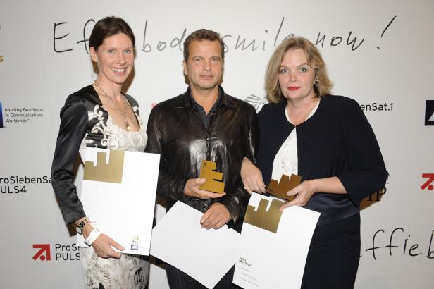 Drei Personen halten goldene Effie Awards und Urkunden in die Kamera.