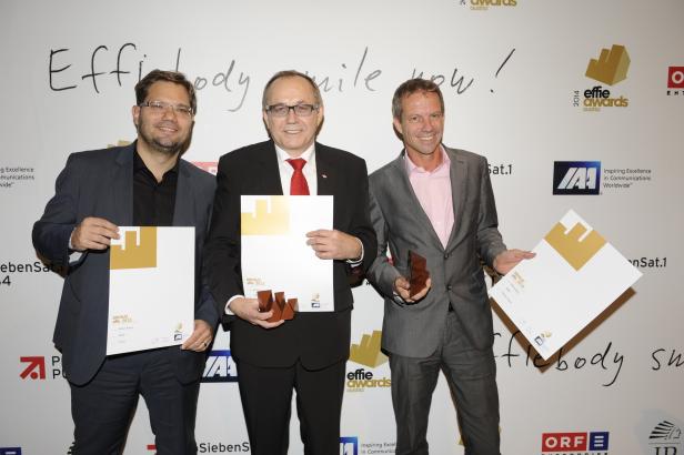 Drei Männer in Anzügen posieren mit Bronze Effie Awards Austria 2013 vor einer Wand mit Logos.