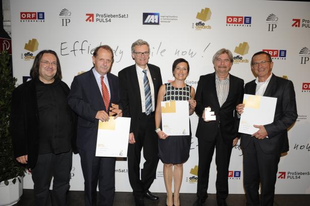Eine Gruppe von Personen posiert mit ihren Effie Awards Austria vor einer Wand mit Logos.