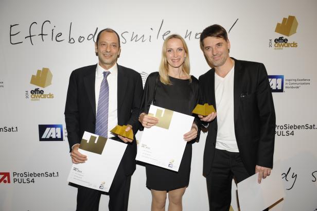Drei Personen halten Urkunden und goldene Trophäen der Effie Awards Austria in den Händen.