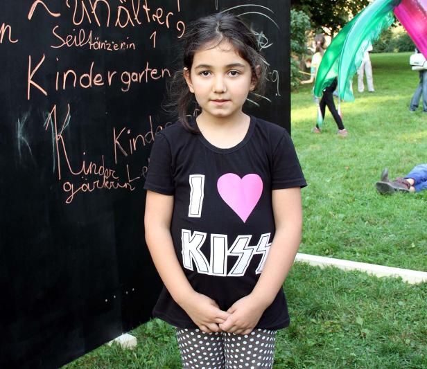 Ein junges Mädchen steht vor einer Tafel mit der Aufschrift „Kindergarten“.