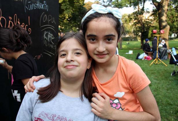 Zwei lächelnde Mädchen umarmen sich im Park.