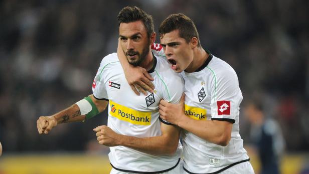 Zwei Fußballspieler von Borussia Mönchengladbach umarmen sich jubelnd.