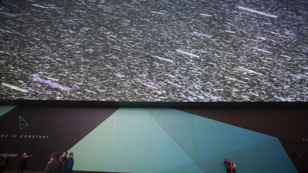 Menschen stehen vor einer großen Leinwand mit einer abstrakten Darstellung des Weltraums.