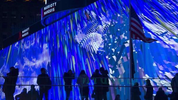 Besucher betrachten eine Kunstinstallation vor dem Marriott Marquis Hotel mit amerikanischer Flagge.