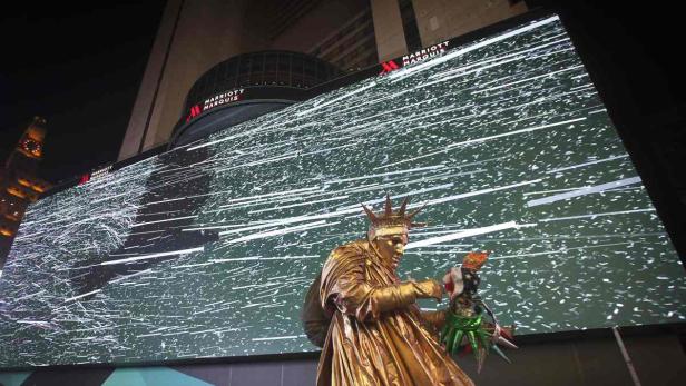 Eine goldene Statue der Freiheitsstatue steht vor einer großen LED-Wand des Marriott Marquis Hotels.